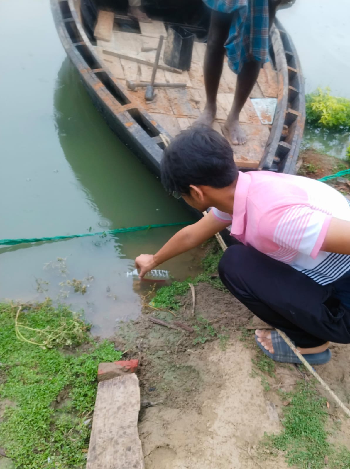 Manan collecting a surface water sample near the boats